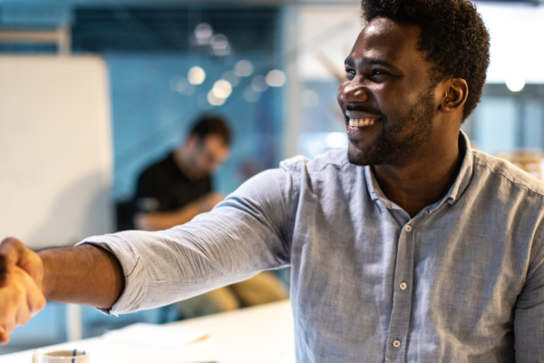 Man in office shakes hand of colleague and smiles